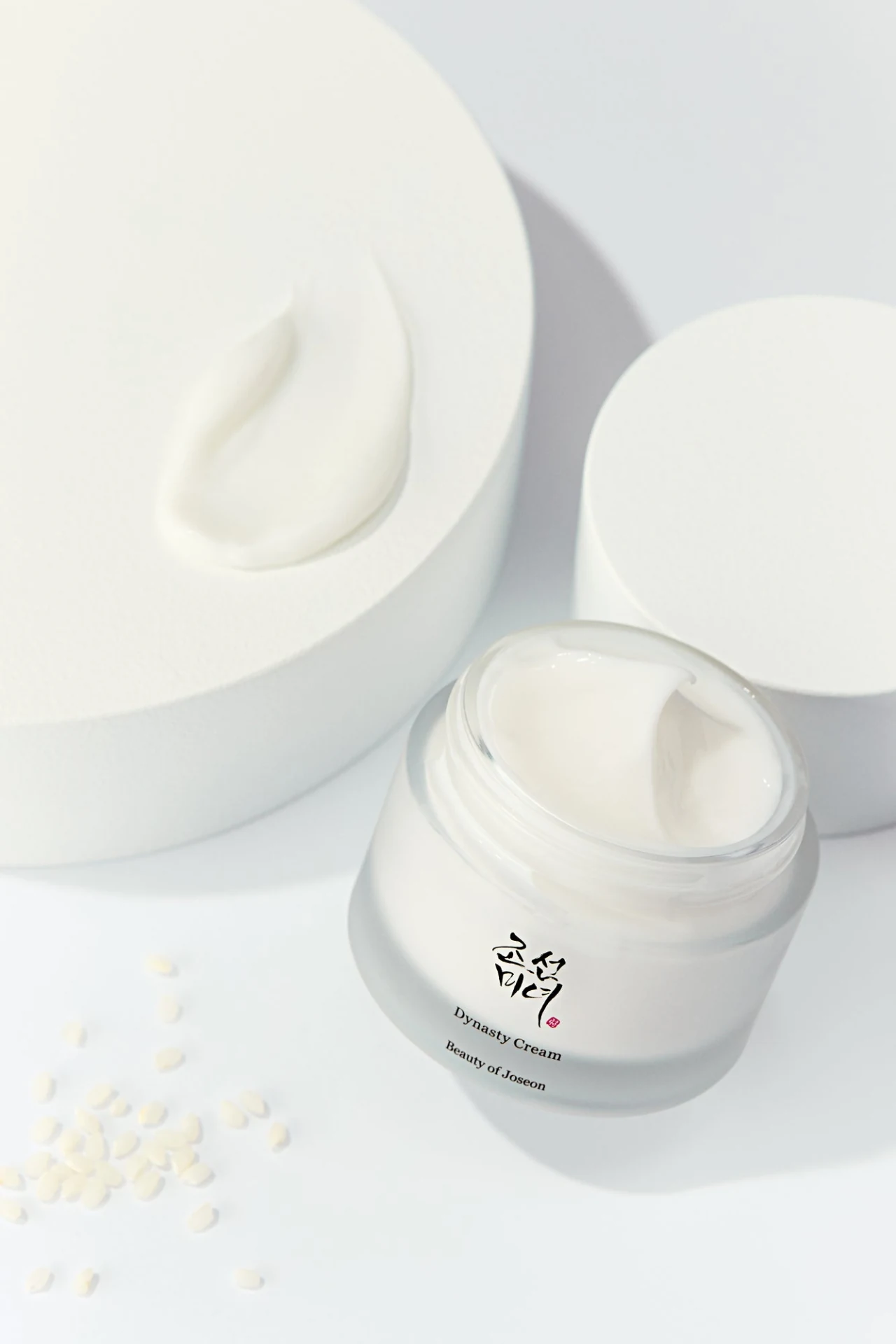 Offener Tiegel Beauty of Joseon Dynasty Cream neben einer kleinen Menge Creme und Reiskörnern