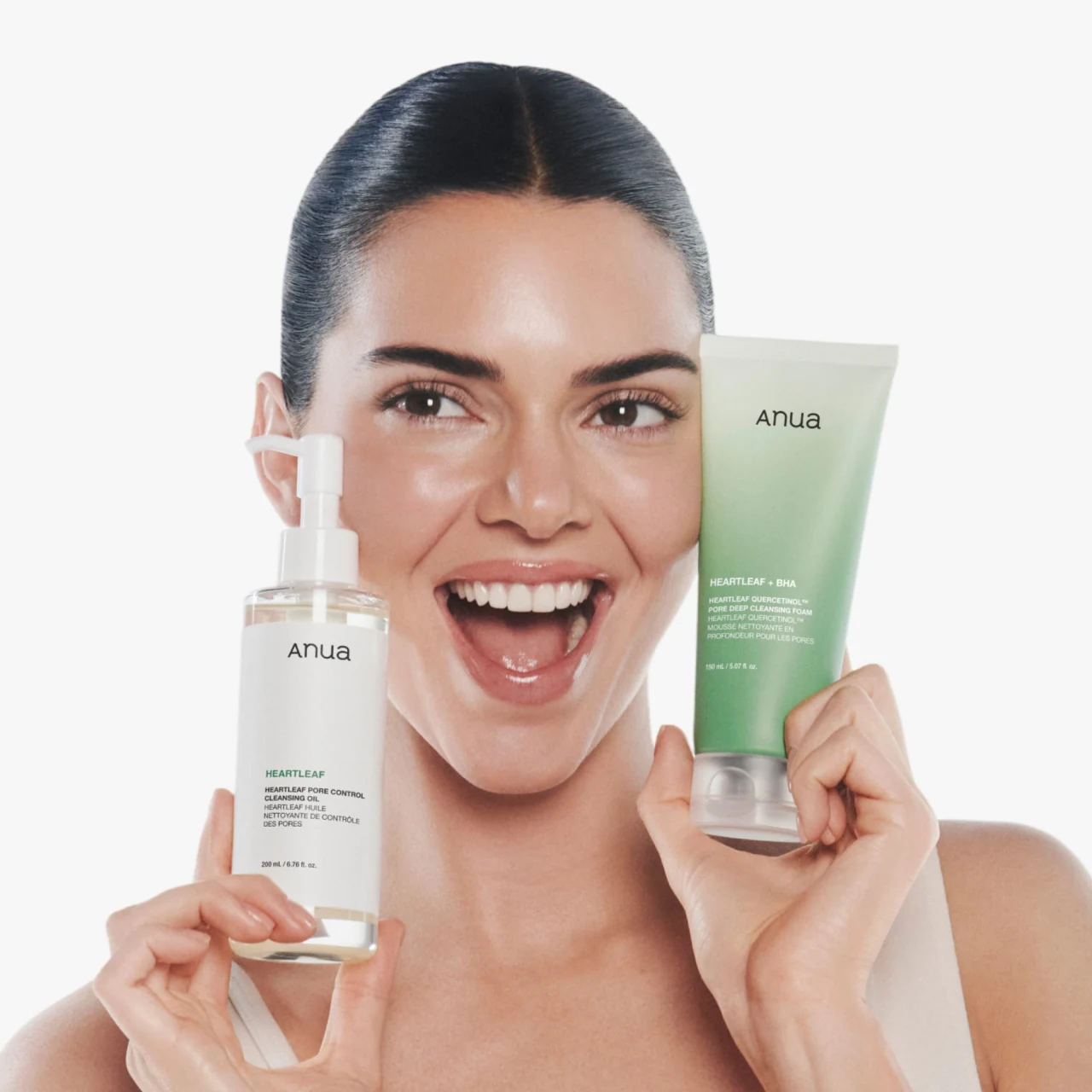 Anua campaign portrait of a model holding Heartleaf cleansing oil and cleansing foam