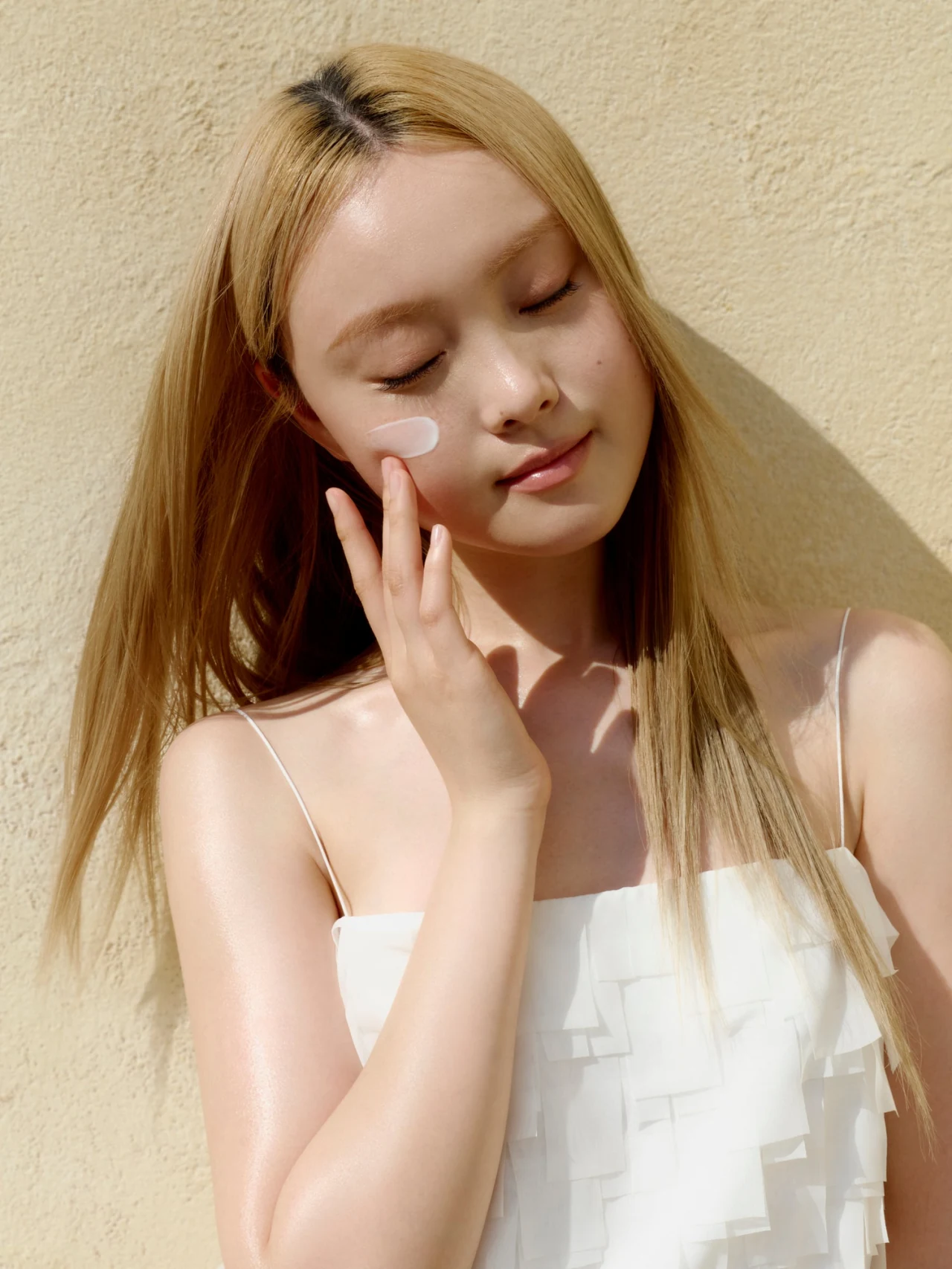 Model dat witte gezichtscrème op haar wang aanbrengt in de Beauty of Joseon-fotoreportage van oktober 2026